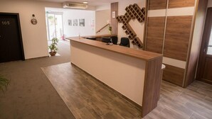 A reception desk with a wooden finish, a potted plant, and a wall-mounted decorative piece. - Villa Angy (Plitvicka Jezera)