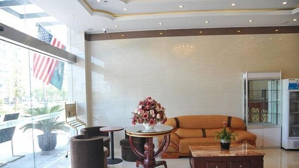 A lobby with a sofa, a round table with a vase of flowers, a coffee table, and a large American flag.