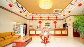 A hotel lobby with a reception desk, a sofa, a coffee table, and a potted plant.