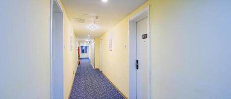 A hallway with a patterned carpet, white walls, and doors with room numbers.