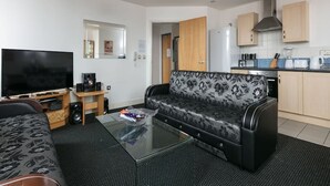 A modern living room with a flat-screen TV, a sofa, and a coffee table. - My-Places City Living Apartment 06 (Manchester)