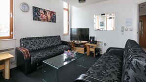 A modern living room with a sofa, a coffee table, a flat-screen TV, and a painting on the wall. - My-Places City Living Apartment 06 (Manchester)