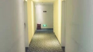 A hallway with a patterned floor leading to a door with a sign above it.