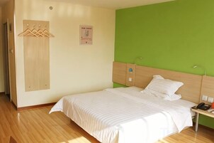 A bedroom with a bed, a nightstand, a wooden wardrobe, and a green wall.