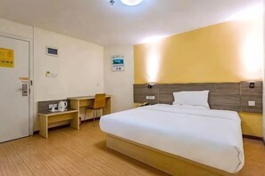 A hotel room with a bed, desk, chair, and a small table.