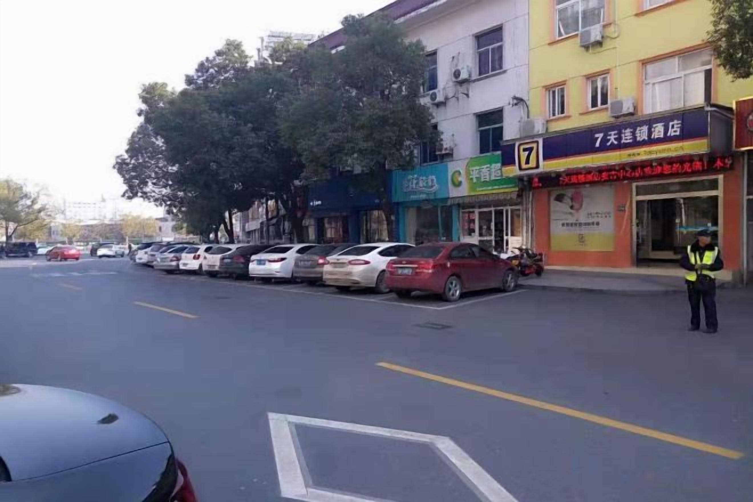 Una calle con coches aparcados y un edificio con un cartel.