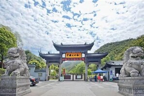 A traditional Chinese gate with stone lion statues on either side, leading to a building with a tiled roof. - 7Days Inn Chain Hotel (Anji Center) (Huzhou)