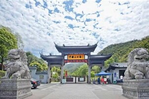 Una puerta tradicional china flanqueada por estatuas de leones de piedra, que conduce a un edificio con tejado de baldosas.