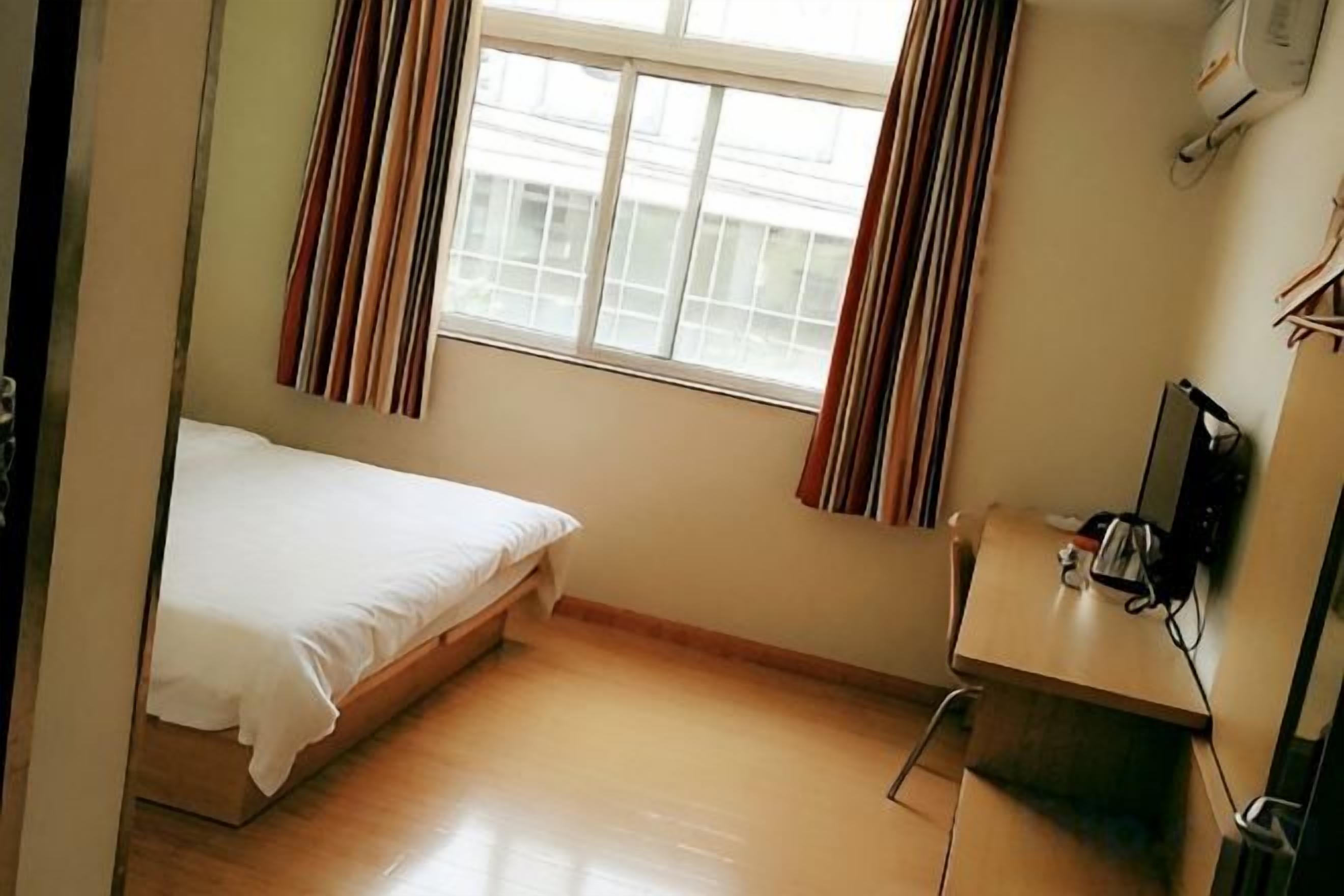 A small, single-bed room with a desk and a chair.