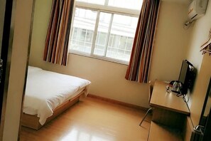 Quarto pequeno com uma cama de solteiro, escrivaninha e cadeira.