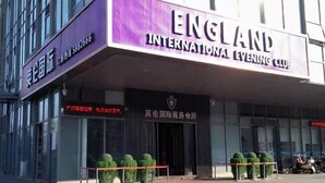 The exterior of the England International Evening Club with a prominent entrance, a signboard, and a gated entrance.