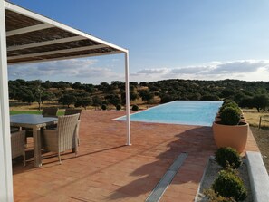 Un espace piscine agrémenté d’une pergola, de mobilier d’extérieur et offrant une vue sur un paysage vallonné.