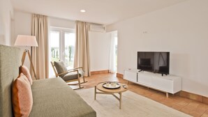 A modern living room with a sofa, a chair, a coffee table, a TV, and a white cabinet. - Herdade do Barrocal de Baixo (Montemor-o-Novo)