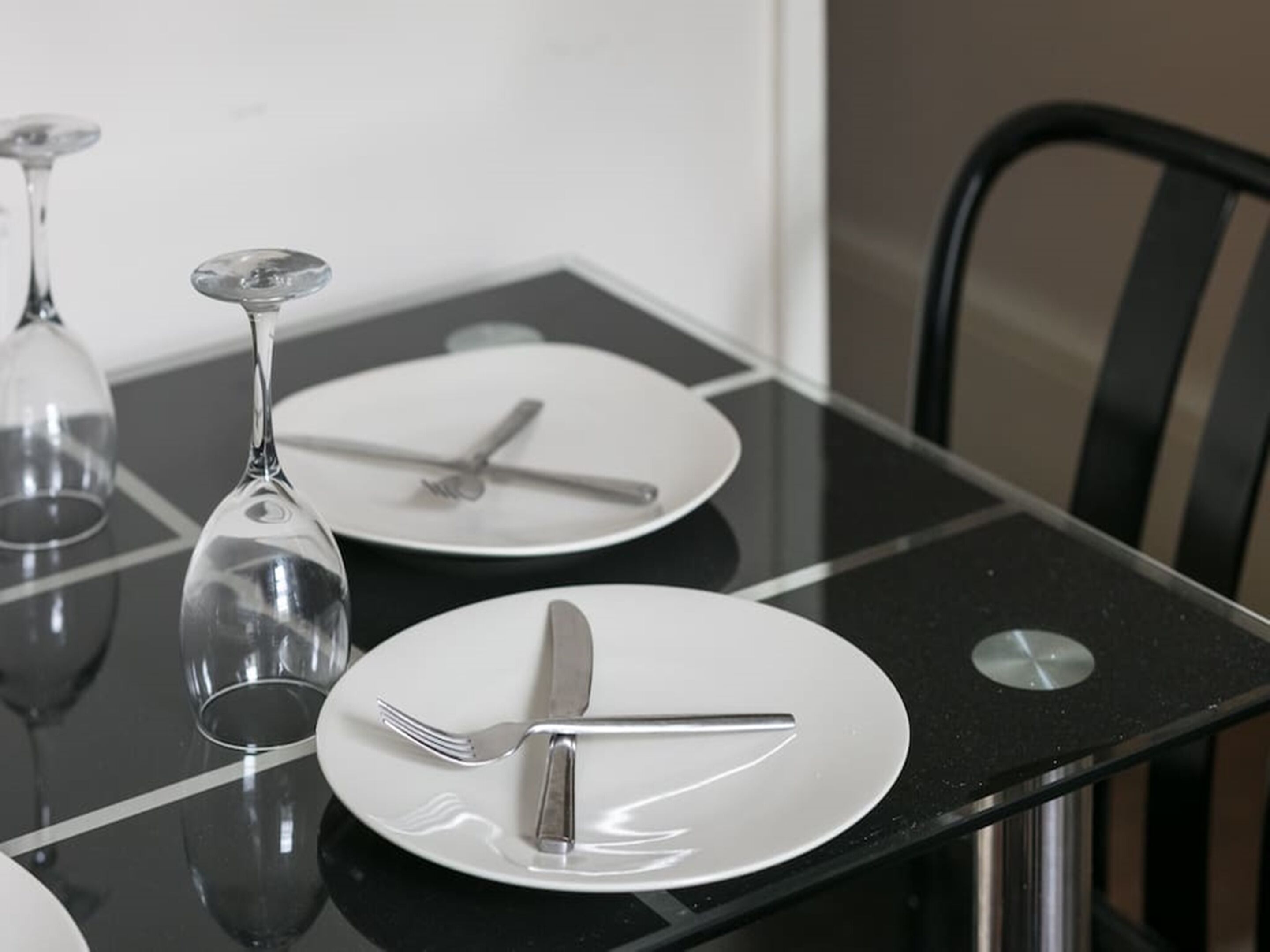 Una mesa de comedor con dos platos, cubiertos y una copa de vino.