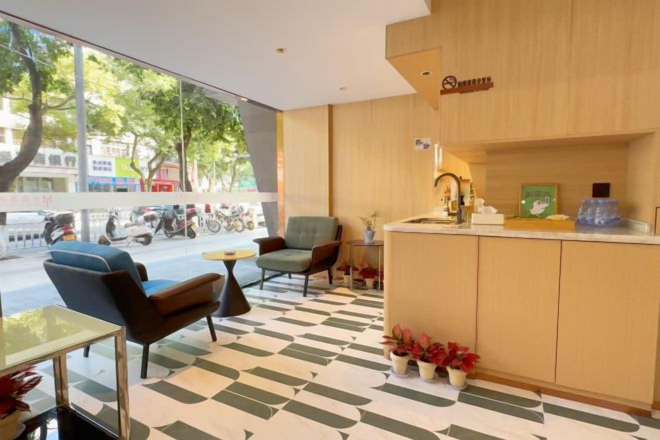 A modern hotel lobby with a reception desk, seating area, and large windows overlooking a street.