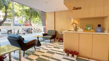 Un vestíbul d'hotel modern amb taulell de recepció, zona de seients i grans finestres que donen al carrer.