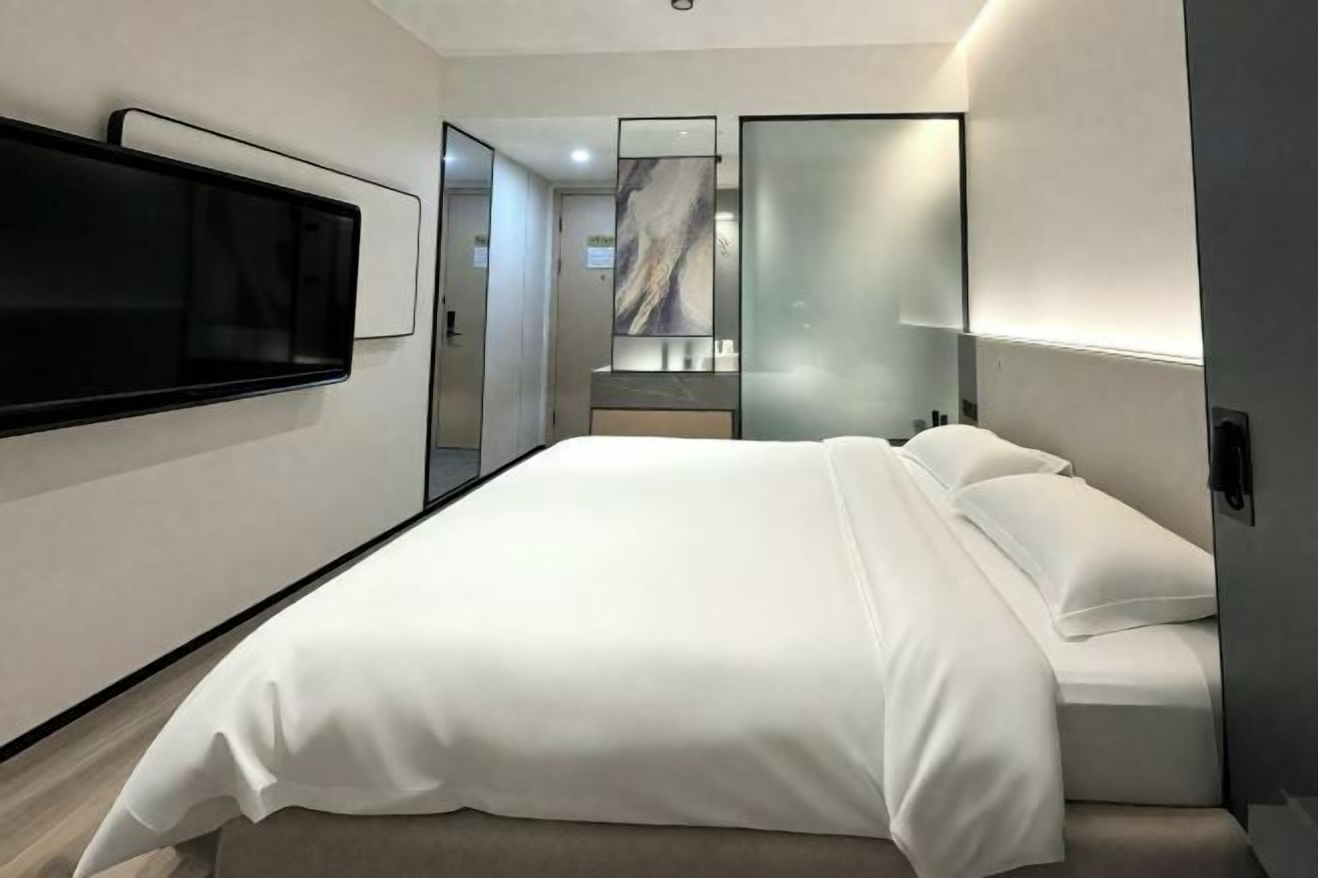 Een moderne hotelkamer met een groot bed, een flatscreen-tv, een spiegel en een wandontwerp van marmer.