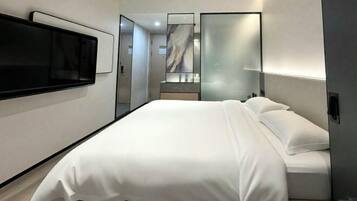 Een moderne hotelkamer met een groot bed, een flatscreen-tv, een spiegel en een wandontwerp van marmer.