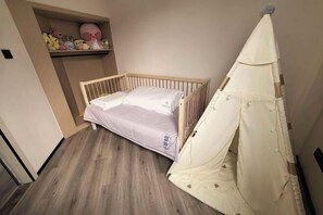 A small, single-bed room with a wooden frame, a white canopy, and a shelf with plush toys. - Crystal Haolaideng Hotel (Dehua)