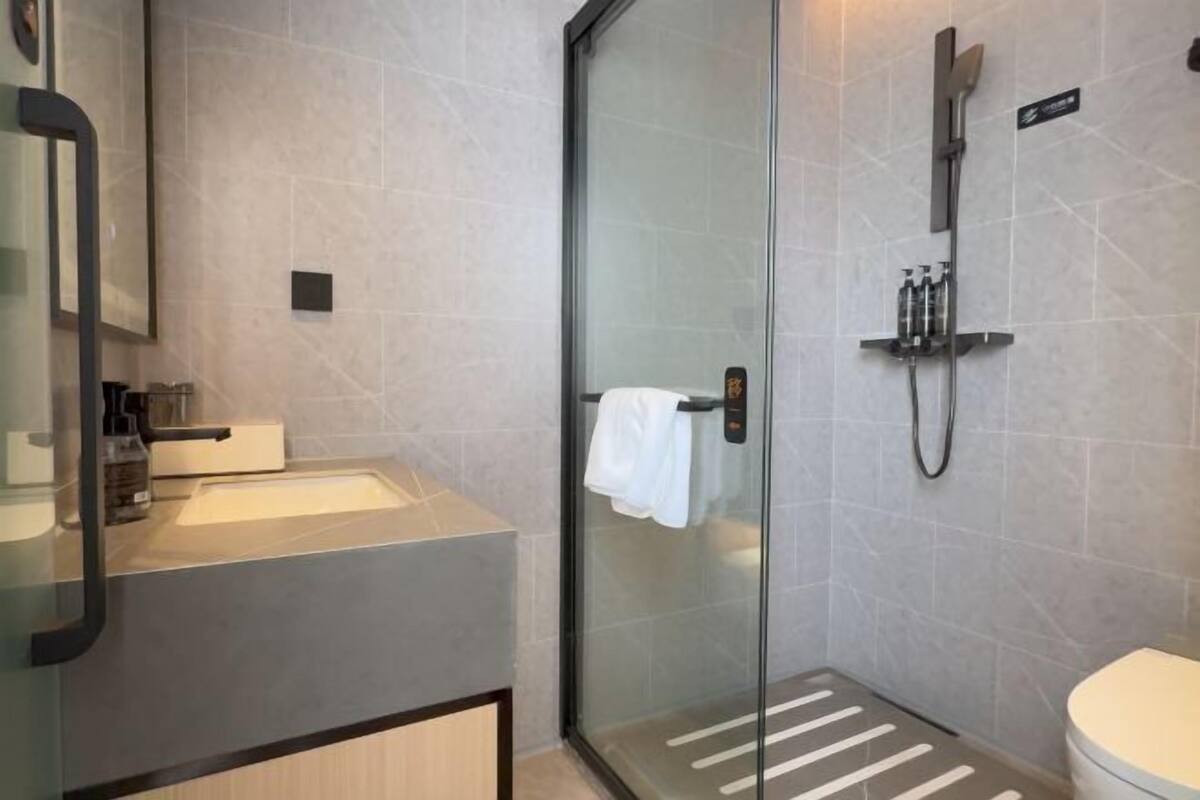 Une salle de bain moderne avec une douche à parois de verre, un lavabo avec un porte-serviettes et des toilettes.
