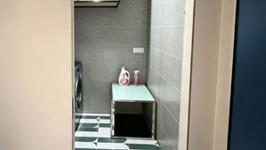A small bathroom with a washing machine, a sink, and a toilet. - Crystal Haolaideng Hotel (Dehua)