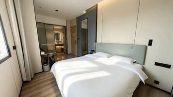 Une chambre d’hôtel moderne avec un grand lit, un bureau et un miroir.