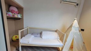 A single bed with a canopy, a shelf with toys, and a small tent-like structure in a room with wooden flooring. - Crystal Haolaideng Hotel (Dehua)