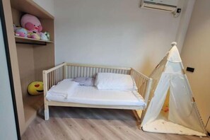 A single bed with a canopy, a shelf with toys, and a small tent-like structure in a room with wooden flooring. - Crystal Haolaideng Hotel (Dehua)