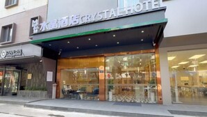 A hotel with a modern facade, large glass windows, and a visible seating area outside. - Crystal Haolaideng Hotel (Dehua)