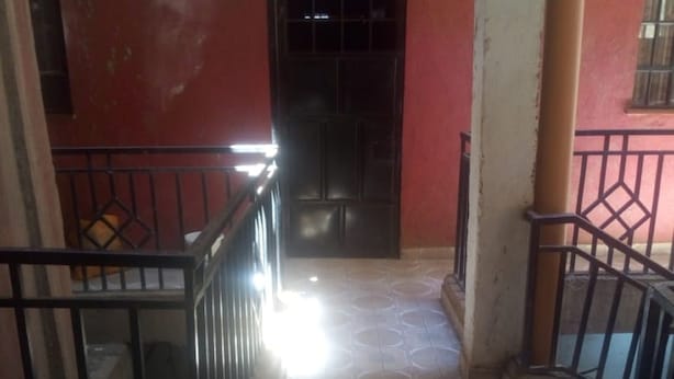 A corridor with a tiled floor, a black door, and a red wall. - Jambo Guest House (Nairobi)