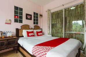 Een hotelkamer met een bed, een nachtkastje, een raam met gordijnen en uitzicht op groen.