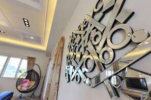 Een modern interieur met een abstracte metalen kunstinstallatie aan de muur, een hangstoel en een fiets.