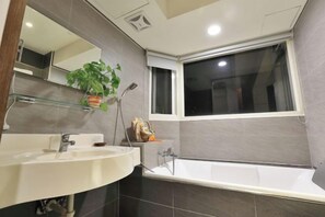 A modern bathroom with a large bathtub, a glass shelf with toiletries, and a window. - relax bnb (Yilan)