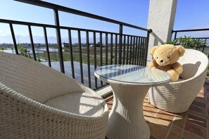 A balcony with wicker furniture, a glass table, and a teddy bear. - relax bnb (Yilan)