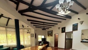 Un'ampia stanza con un grande tavolo in legno, un lampadario e un pavimento piastrellato.