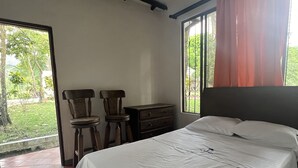 Una camera da letto con un letto, una sedia, un tavolino e una finestra con tende.
