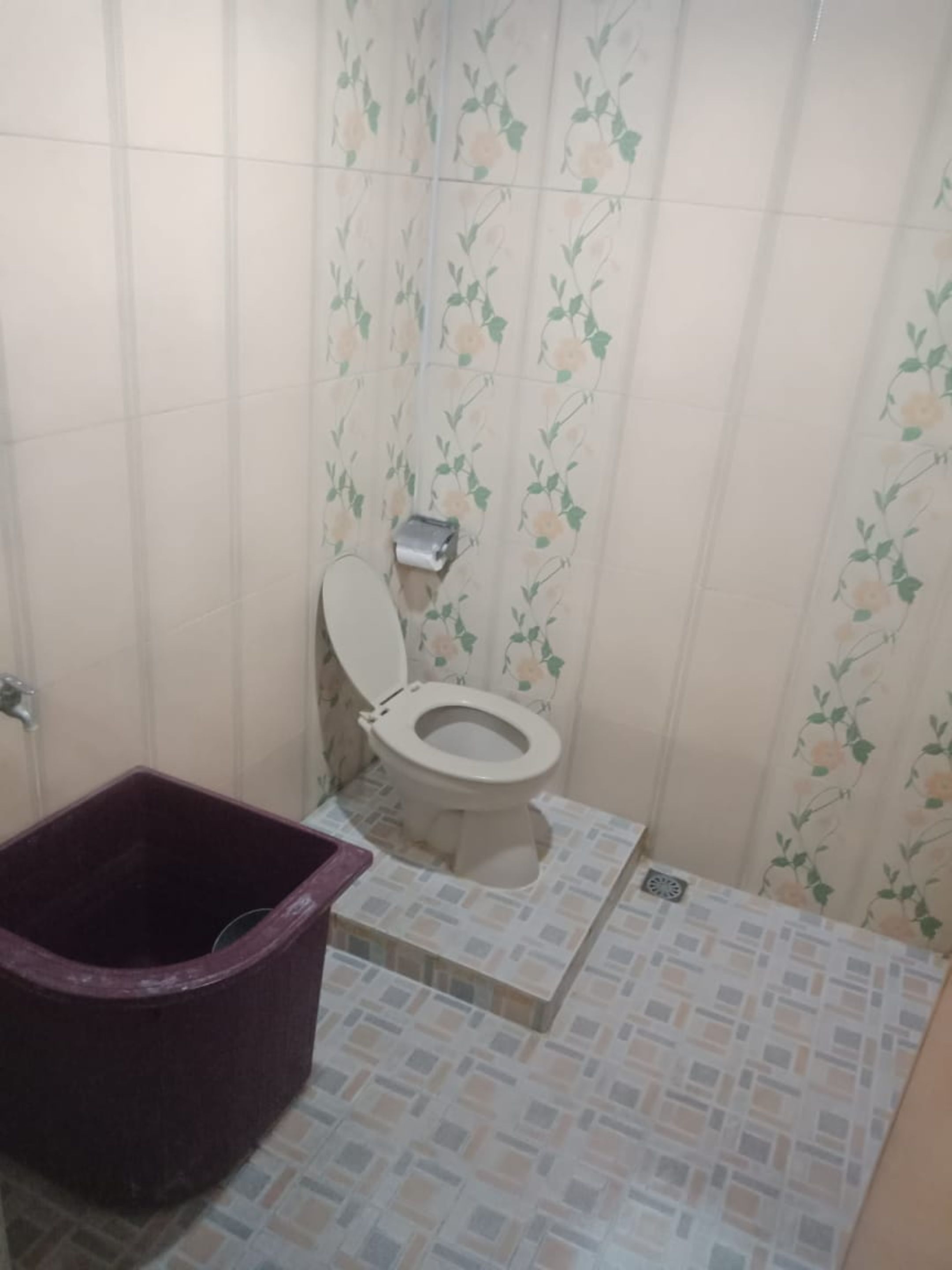 Ein kleines Badezimmer mit Toilette, Mülleimer und Fliesenwänden.