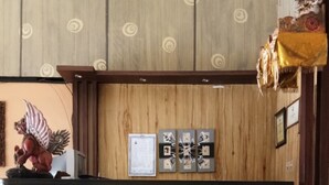 A reception desk with a wooden finish, a decorative angel statue, and framed certificates on the wall. - Duta Karya Hotel (Buleleng)