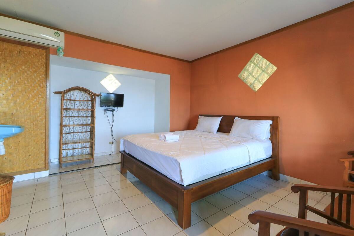 Una habitación de hotel con cama, televisión, ventana y puerta.
