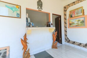Uma área de recepção com um mapa, uma escultura de cabeça de Buda e uma fotografia emoldurada na parede.