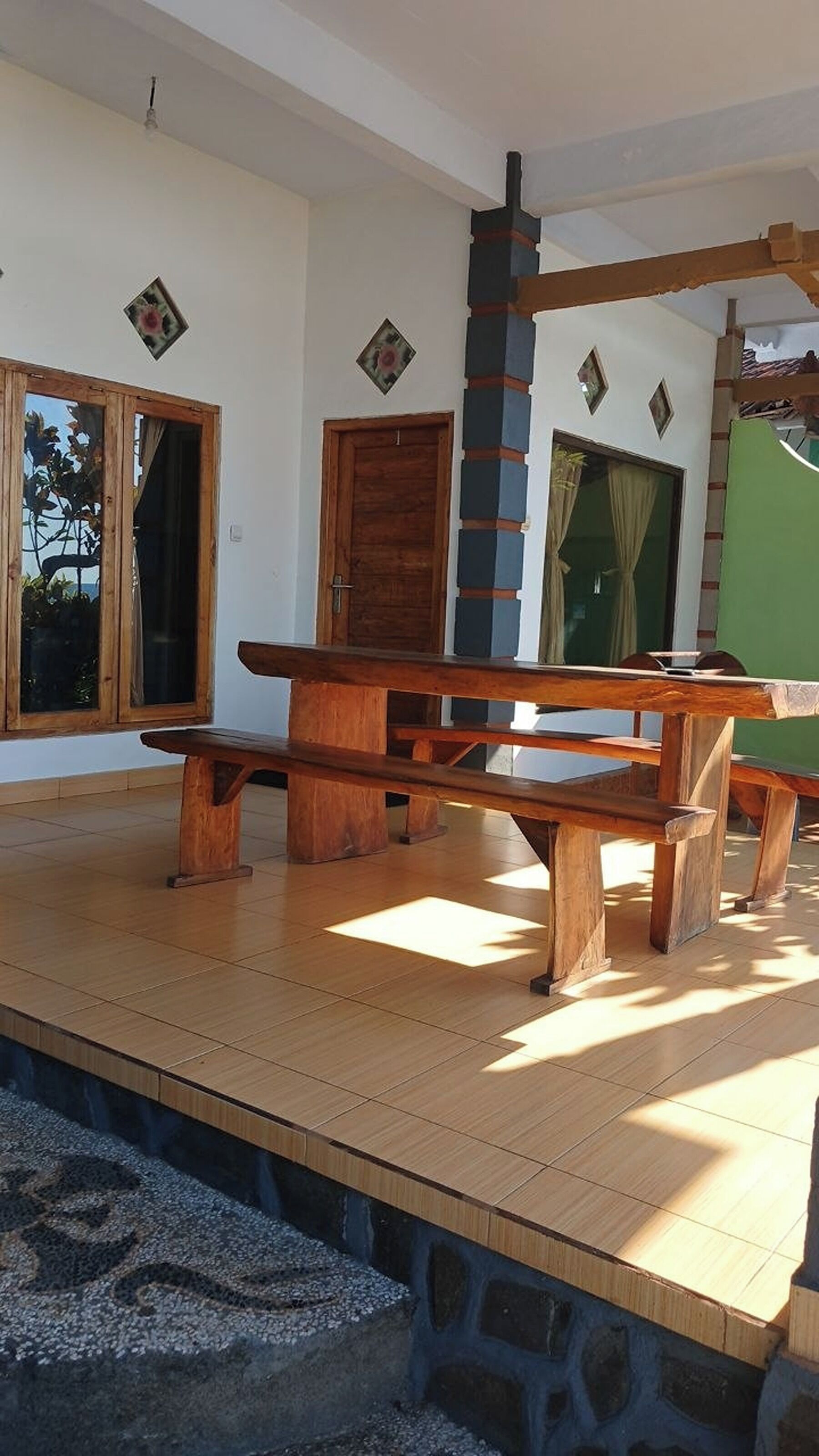 A wooden bench with a stone base in a room with tiled flooring, a wooden door, and a window with a view.
