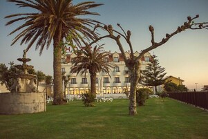 Un hotel con patio central, palmeras, una fuente y mobiliario para exteriores.