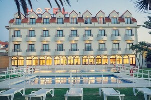 Un hotel con varios balcones, piscina e iluminación exterior destacada.