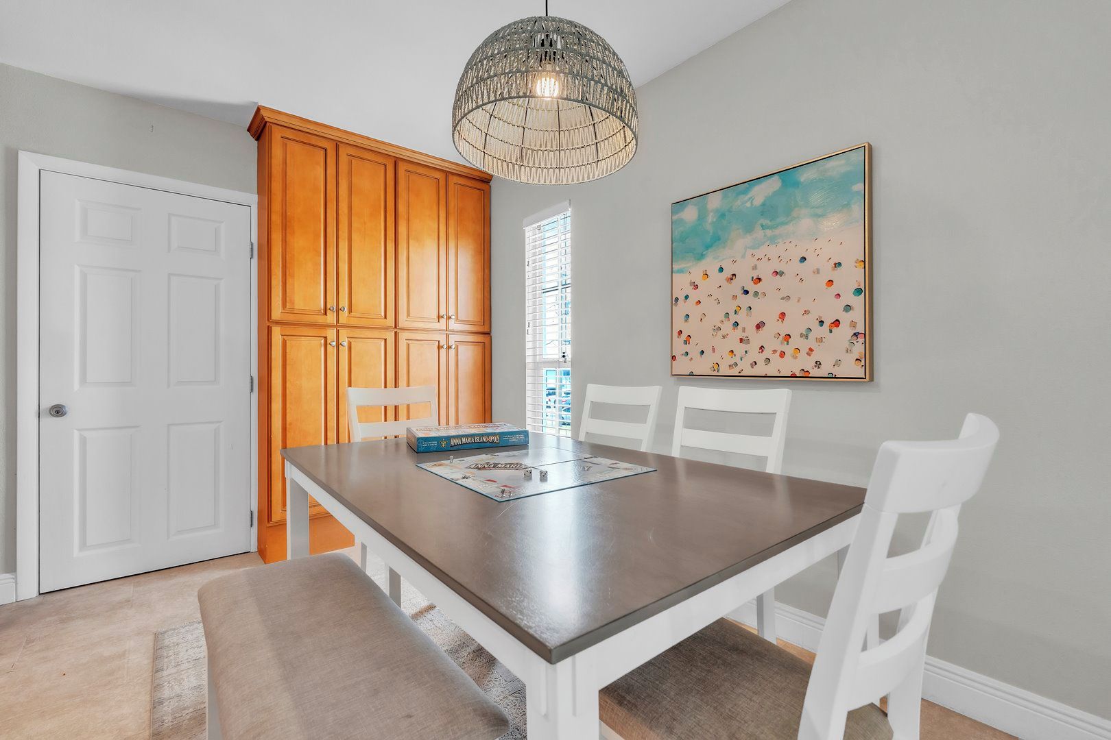 Een eetruimte met een tafel, stoelen, een kroonluchter en een schilderij aan de muur.