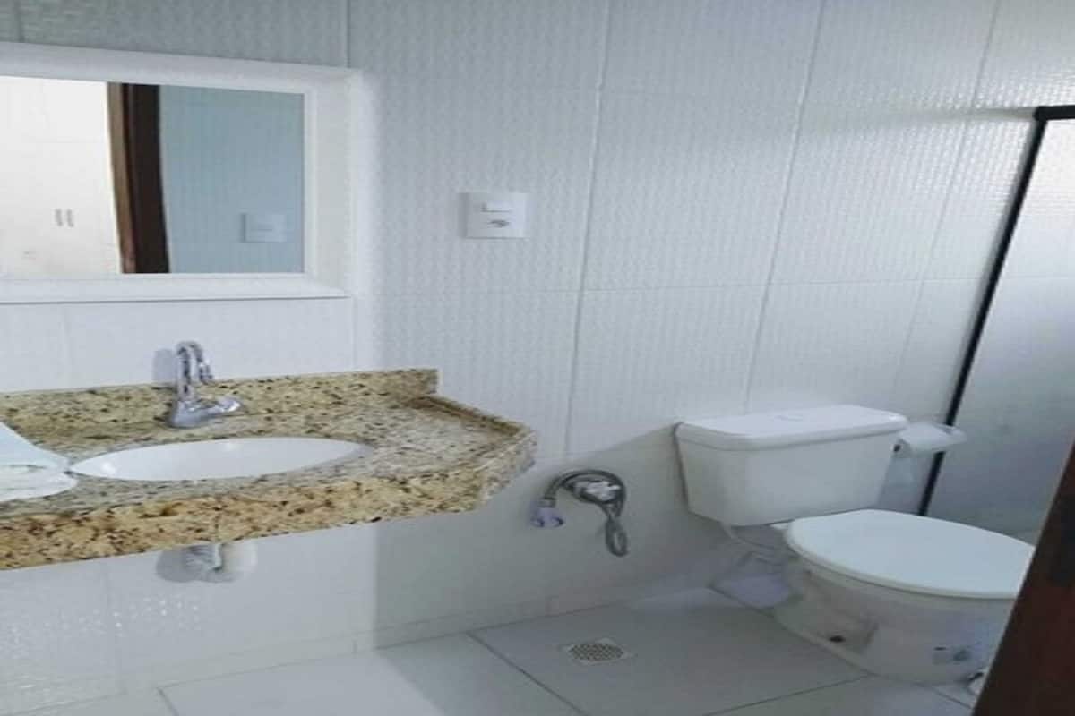 A bathroom with a granite countertop, a white sink, a toilet, and a mirror above the sink.