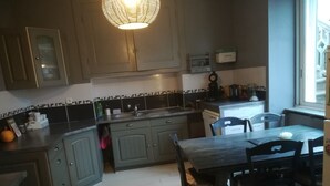 Una cocina con armarios grises, una mesa de comedor de madera y una lámpara colgante.