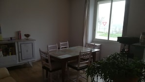 Un comedor con una mesa y sillas, un armario, un ventanal con vistas y una planta en maceta.