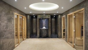 A modern interior with a central light fixture, stone columns, and wooden doors. - Buxton Crescent (Buxton)