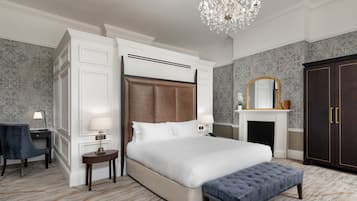 Un'ampia camera da letto con un letto grande, un angolo relax con scrivania e sedia, un lampadario e un armadio.