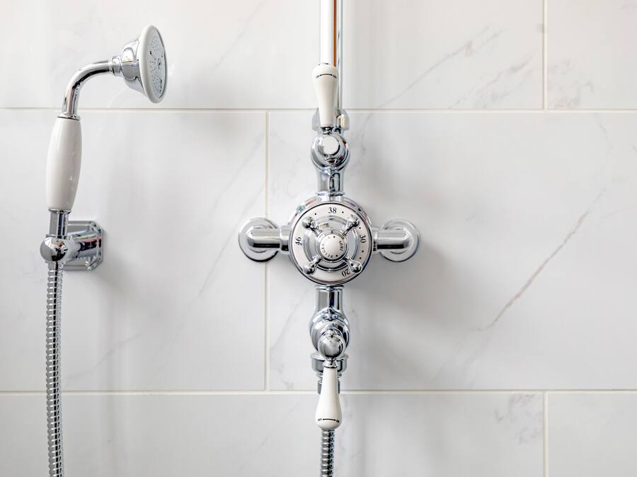 A bathroom with a chrome shower and a handheld showerhead.